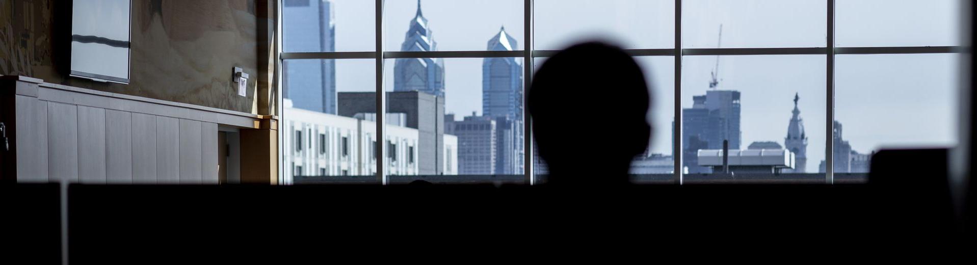 一名学生透过亿德体育大楼的窗户望向费城的天际线.