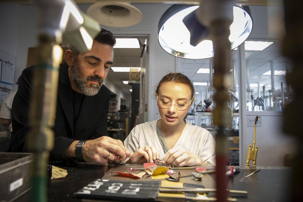 A professor assists a student in the Metals studio.