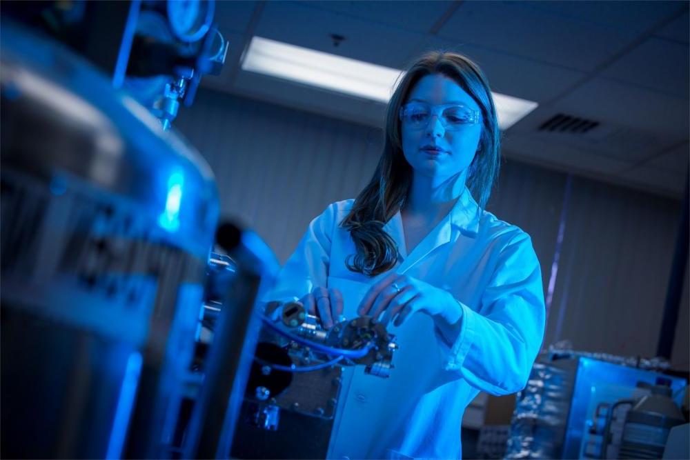 身着实验服，戴着护目镜的生物化学学生正在实验室里调试机器